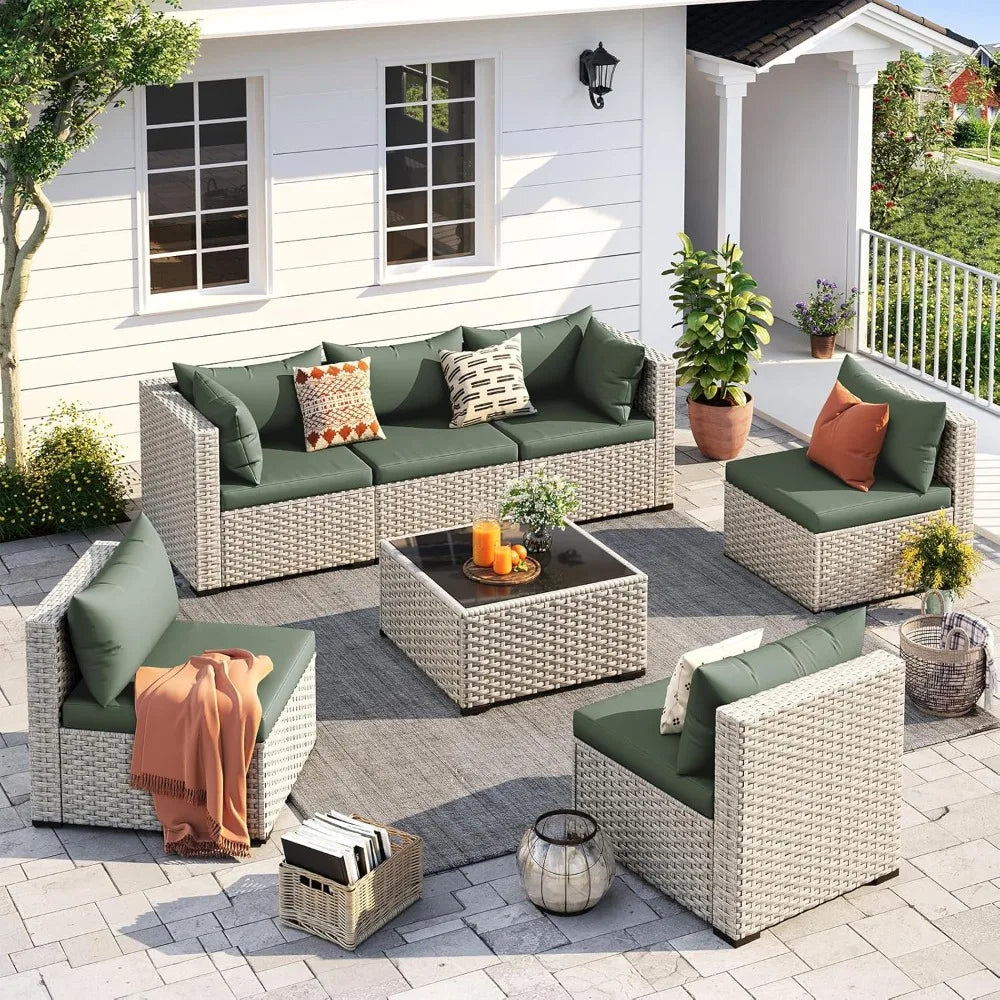 Outdoor patio furniture set with green cushions and orange throws on a patio.