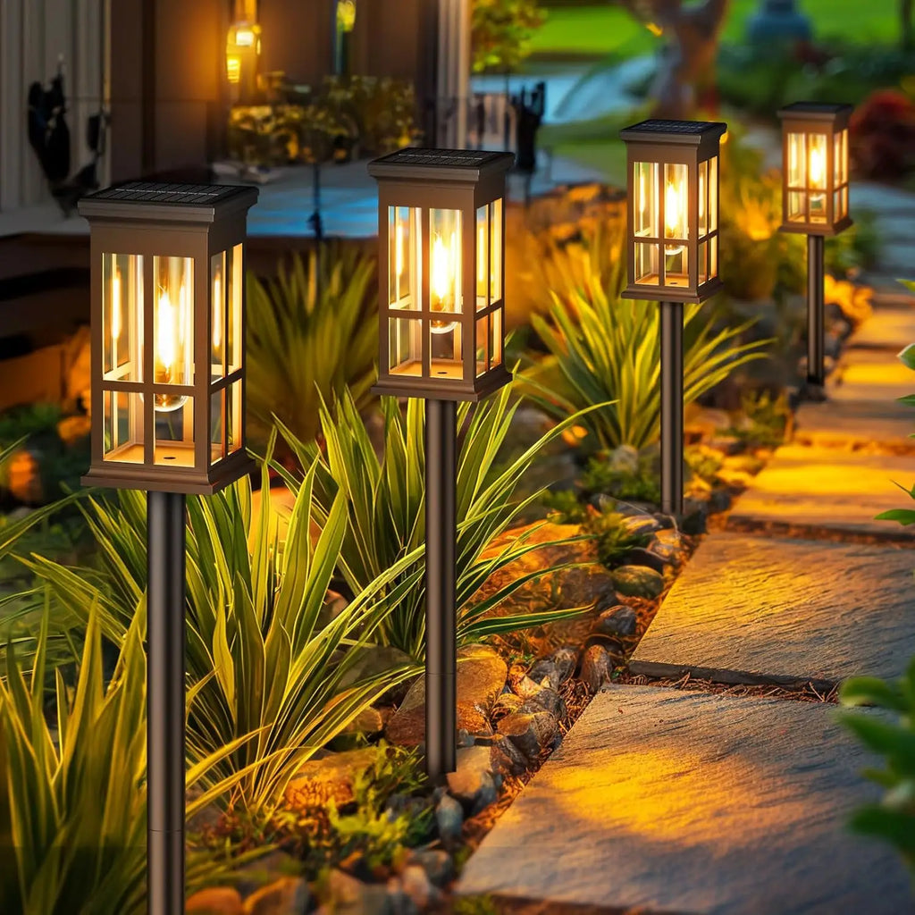 Garden pathway with decorative lantern lights illuminating a garden area.