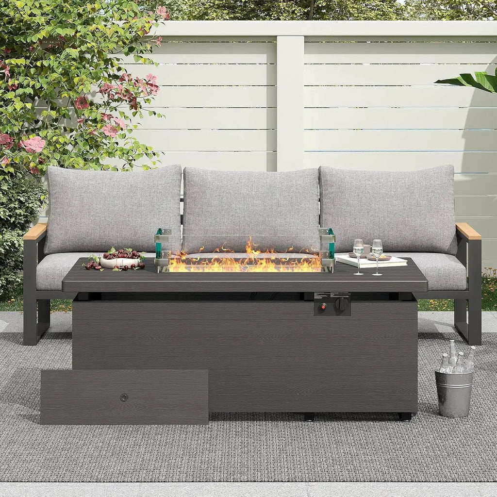 Outdoor patio setup with a fire pit table and gray sofa in a garden setting.